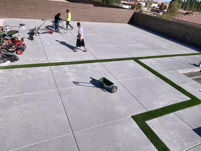 Slab patio, turf inlay, crew finishing, a Unique Pavers job in Las Vegas Valley