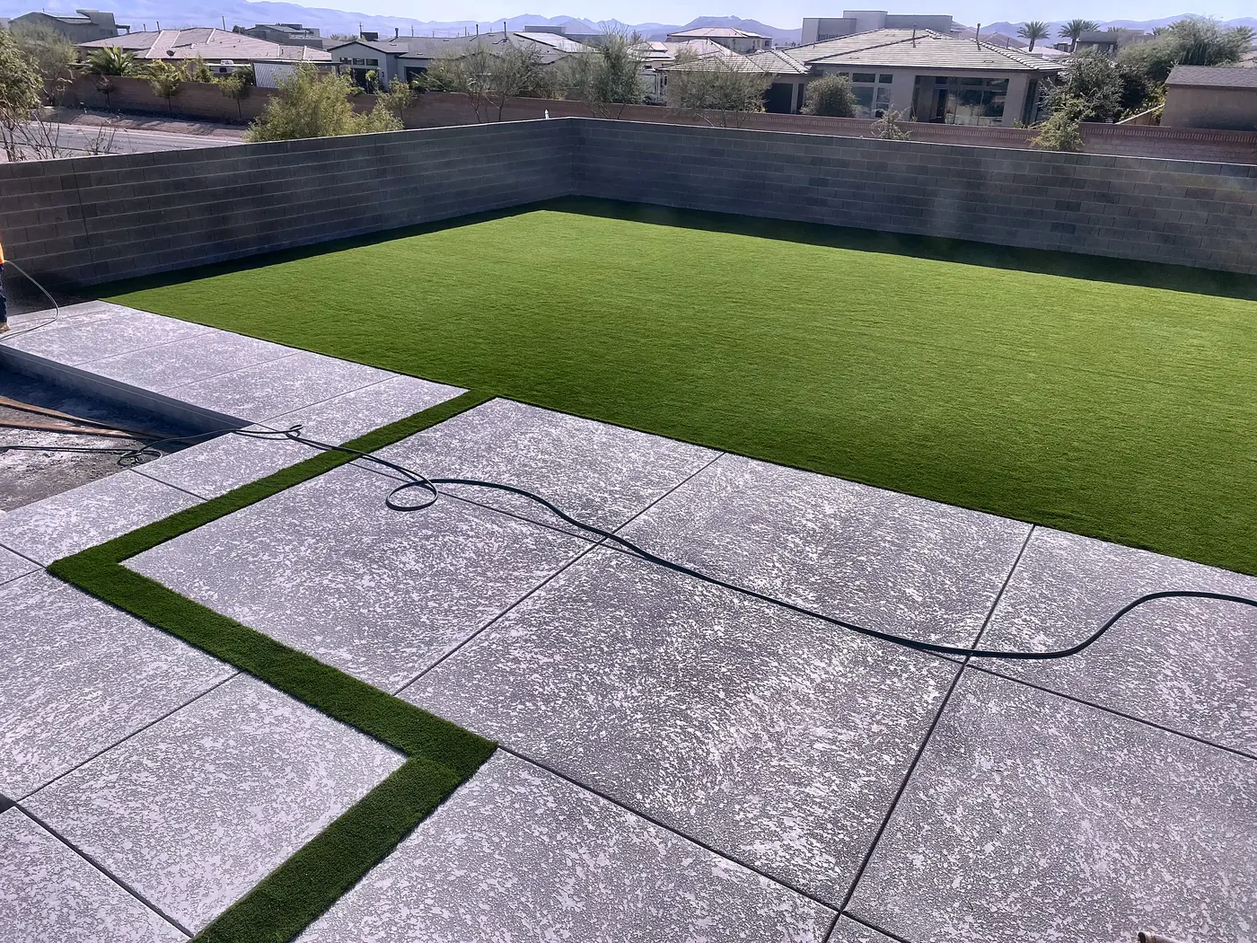 Large slab patio with turf inlay, a Unique Pavers job in the Las Vegas valley