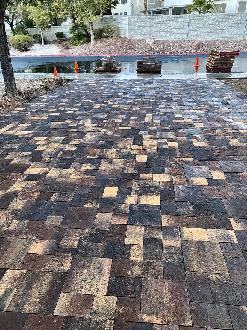 Wide backyard patio in a brown and charcoal blend paver with a pool behind it