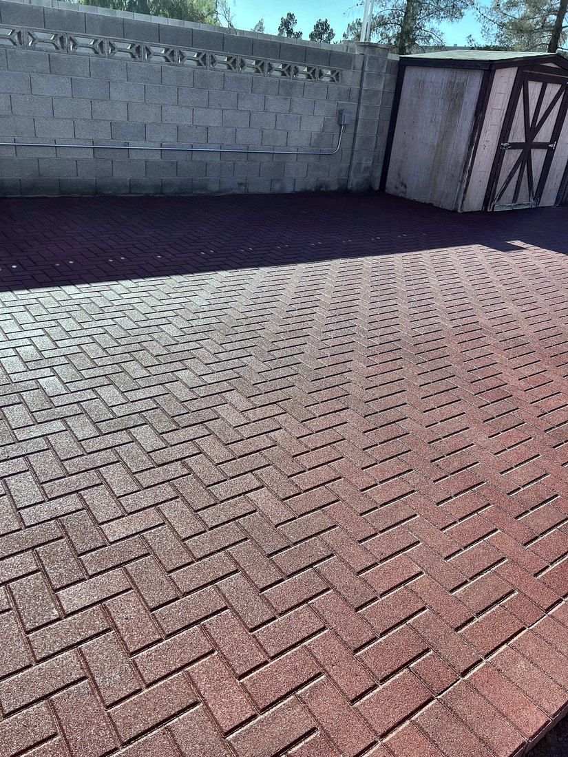 Red herringbone paver driveway inside a block wall with a gate